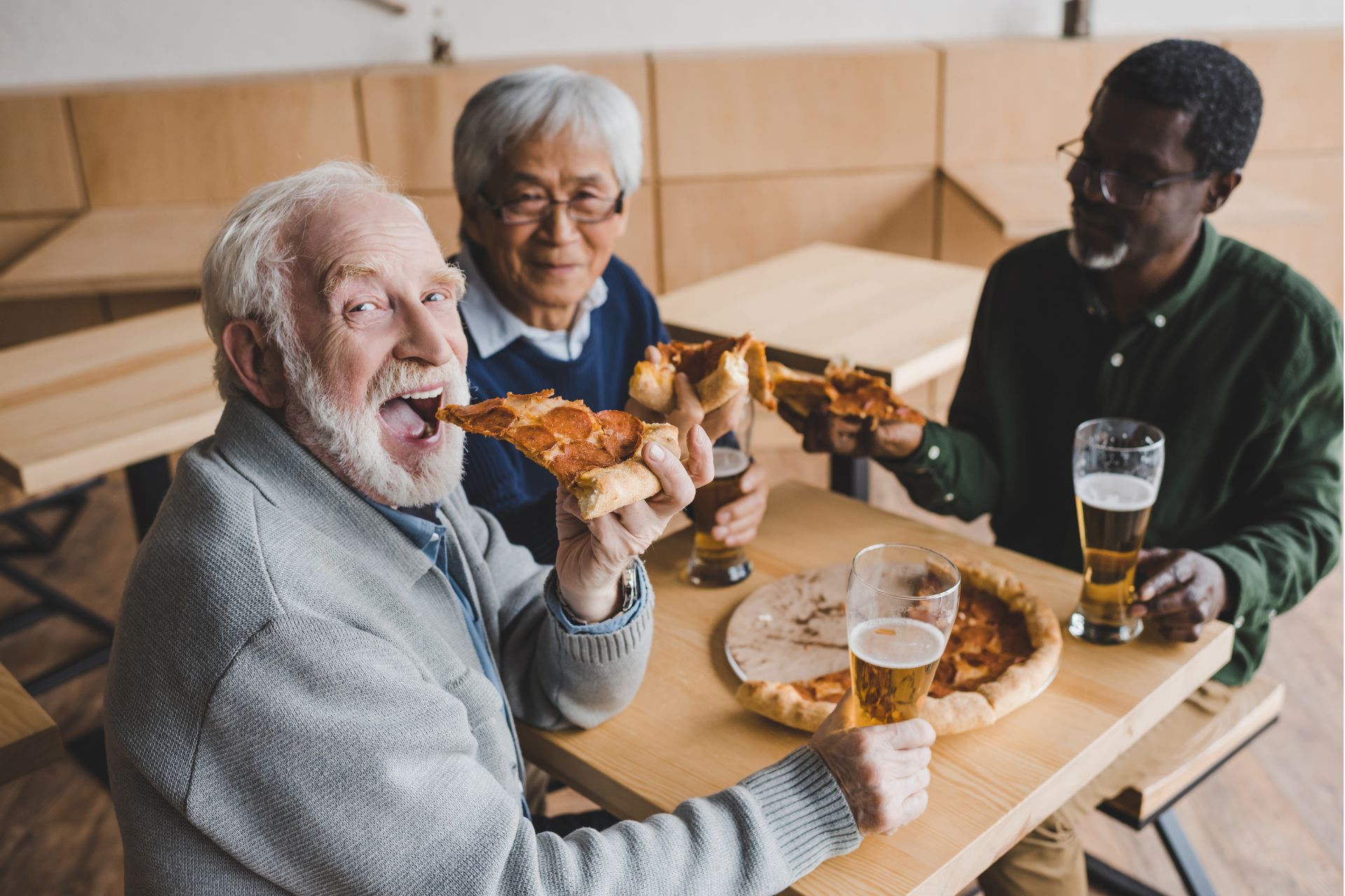 A group of three seniors enjoying pizza
